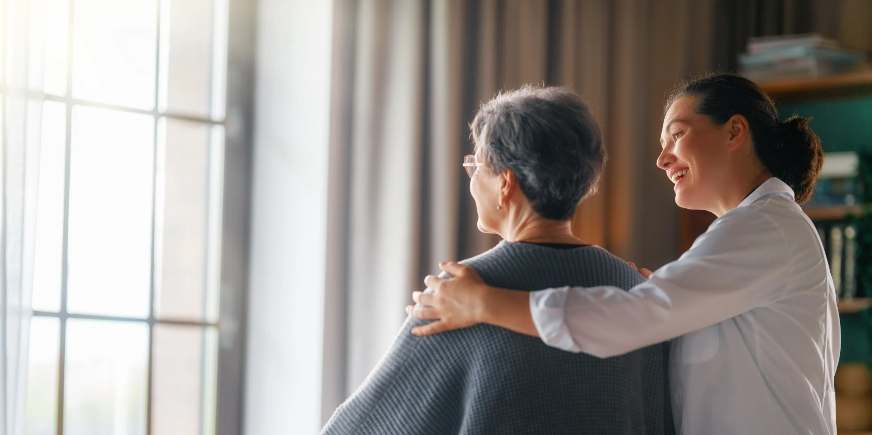 A caregiver embracing a senior resident by a sunlit window